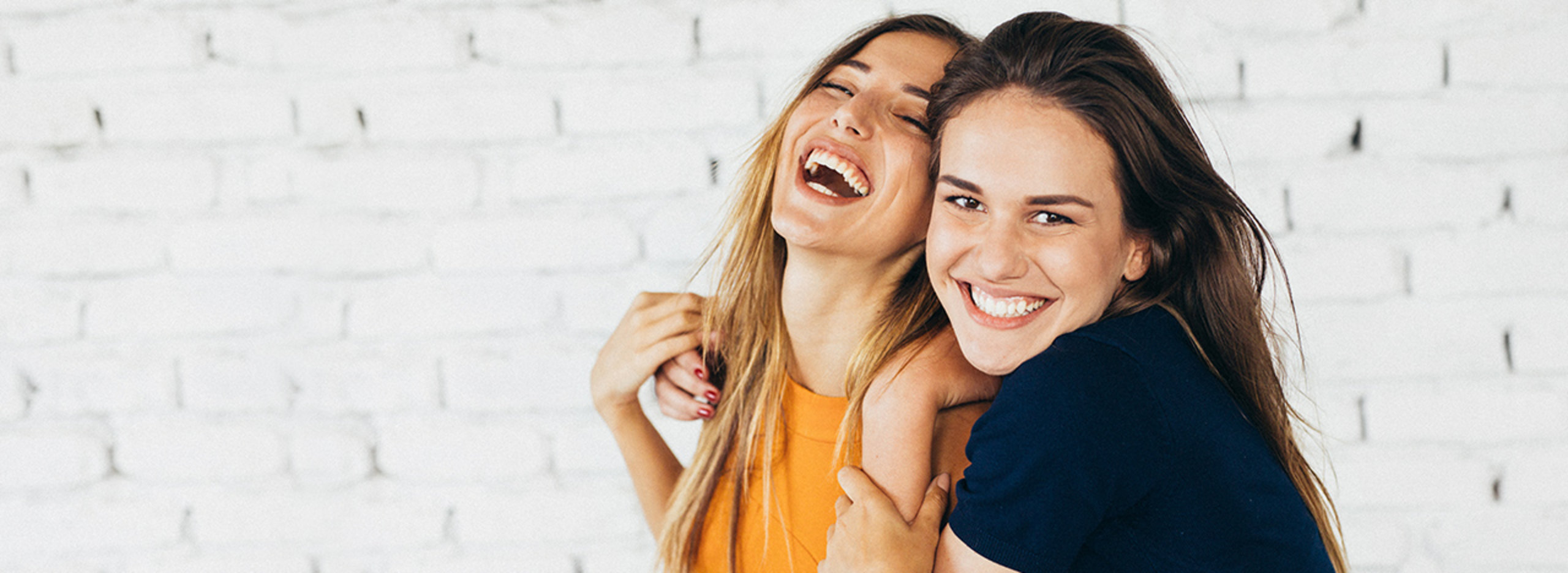 Zwei Frauen umarmen sich und lachen dabei